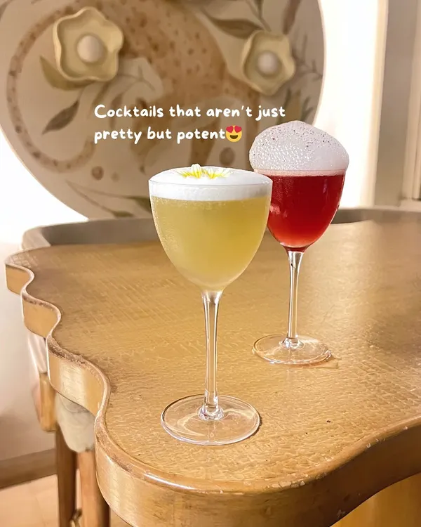 Two elegant cocktails on a uniquely shaped table, hinting at the stylish decor of the bar.