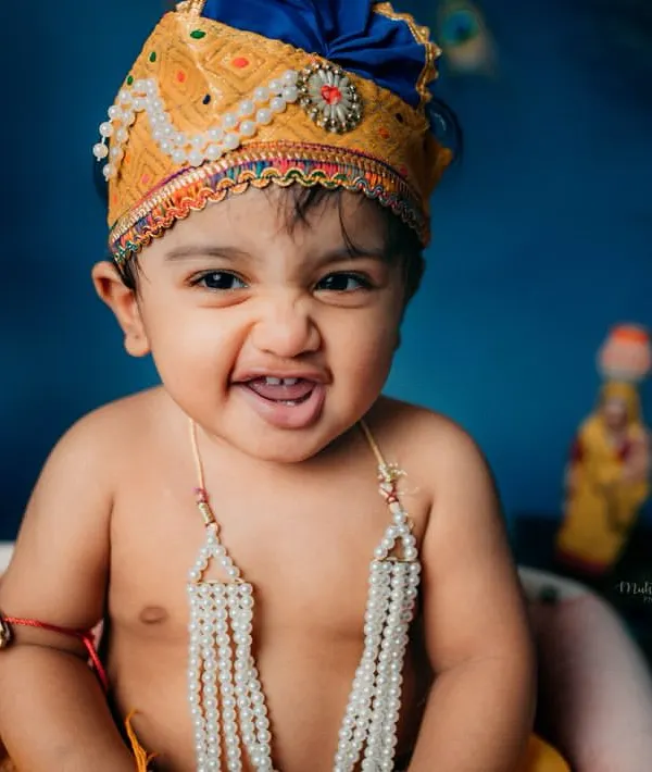 The most infectious, cheeky smile from our little Krishna. This candid shot perfectly captures the playful energy we aim for in these themed festival photoshoots.