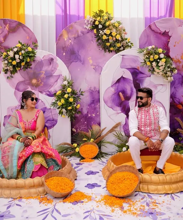 For this haldi, I designed a unique seating arrangement with the couple in separate ornate tubs, ready for the ceremony. The backdrop featured beautiful lavender and yellow watercolor panels with floral accents.
