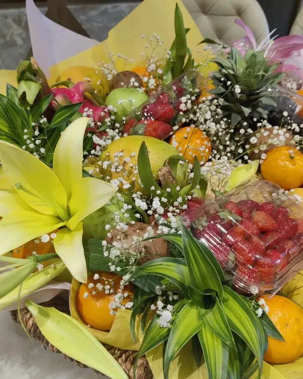 A lush and abundant fresh fruit hamper, perfect for a healthy and elegant corporate gift. This basket is artfully arranged with a variety of exotic and seasonal fruits like strawberries, dragon fruit, and pineapple, accented with fresh lilies and baby's breath.