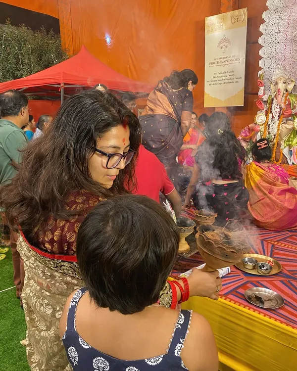 A woman participates in the Dhunuchi Naach, the fragrant smoke from the earthen pot creating a mystical atmosphere. This is a key ritual of Durga Puja celebrations.