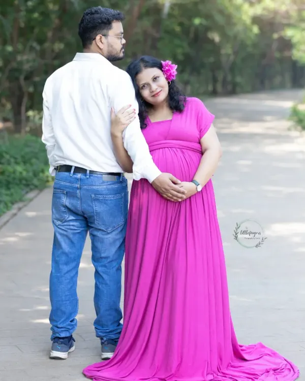An expecting mother in a vibrant pink gown leans lovingly against her partner. This outdoor maternity portrait captures the quiet strength and connection between parents-to-be.