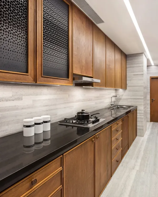 The kitchen in the Limestone Residence features custom cabinetry crafted from teak with a natural linseed oil polish. The perforated cabinet doors add a decorative yet functional detail, while the stone backsplash and countertops provide a durable and elegant surface.