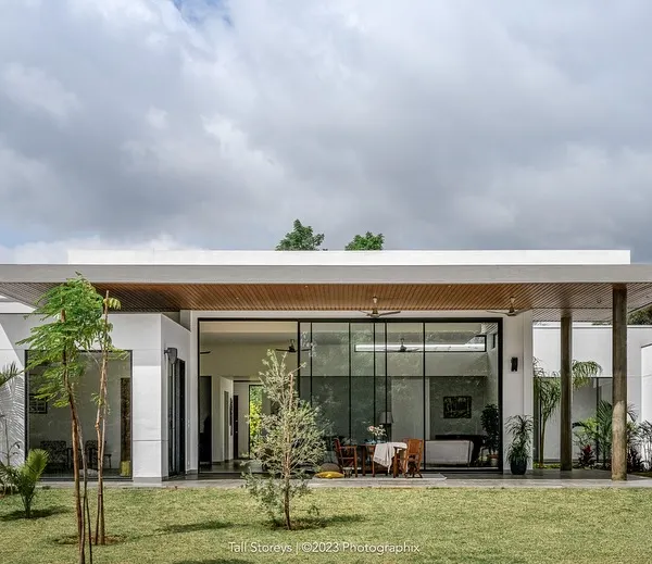 The "Nisarg" residence, where a striking floating slab rests on sleek pilotis, forming a covered leisure space that extends into the lush green landscape. The architecture is deliberately minimal to let nature take center stage.