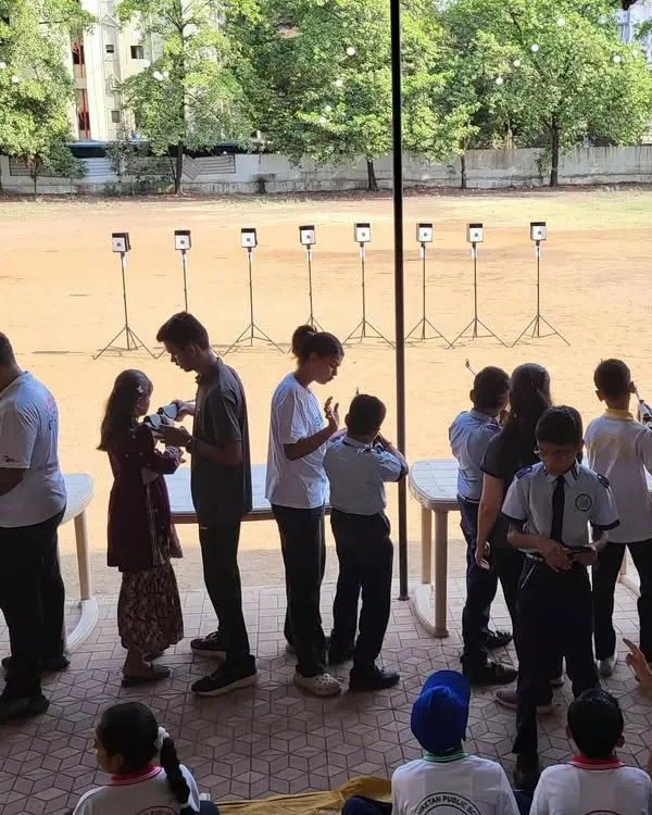 A wide shot of a free workshop conducted at a local school. You can see a long line of students eagerly waiting to try their hand at rifle shooting, showing the immense interest we generate with these outreach programs.