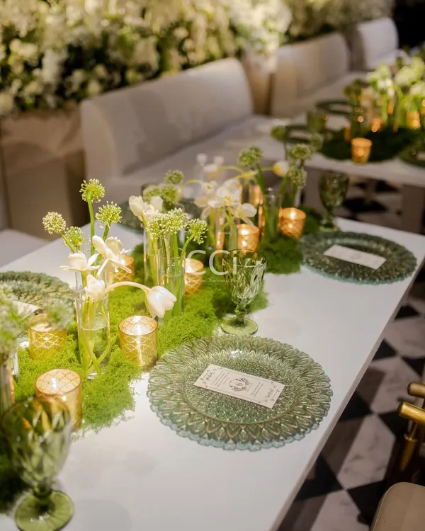 We believe an event begins with the ambiance. Here is an elegant tablescape we designed, featuring lush green moss runners, delicate white florals, and textured glassware to create a sophisticated, garden-like atmosphere for a luxury social event.