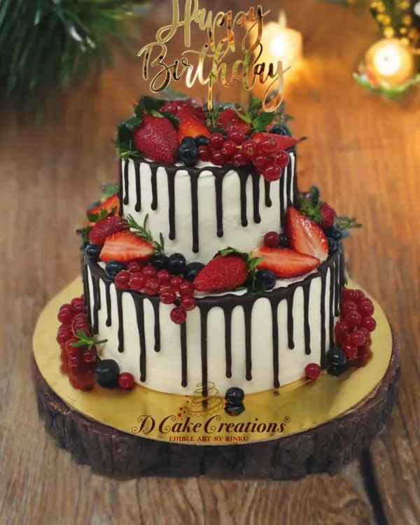 A delicious two-tier drip cake, generously topped with fresh strawberries, blueberries, and red currants. It's the perfect blend of elegance and freshness.