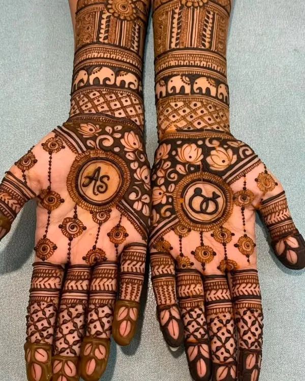 A perfect engagement mehndi design featuring the couple's initials 'AS' on one palm and interlocking rings on the other.