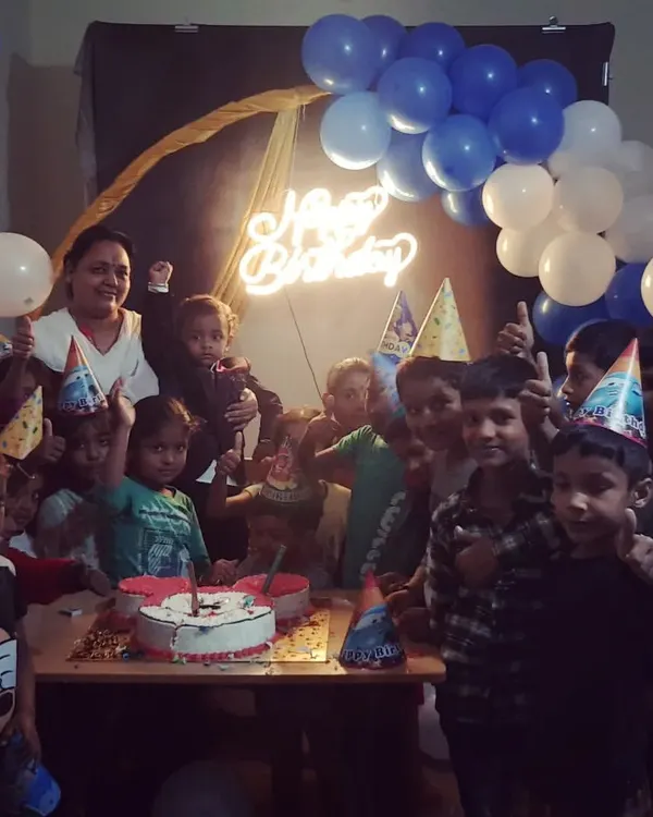 Even a simple setup can bring so much joy. Here, we created a fun party atmosphere with a blue and white balloon backdrop, a glowing neon 'Happy Birthday' sign, and party hats for all the kids to enjoy the cake-cutting ceremony.