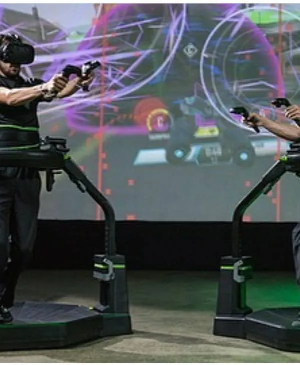 Two participants fully engaged in a competitive VR game on our Virtuix Omni treadmills. This setup allows for 360-degree movement, making it a perfect centerpiece for corporate team-building events and brand activations that require high energy.