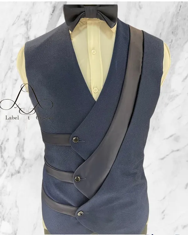 This is not your average waistcoat. The unique asymmetrical design with satin strap details makes it a true statement piece, perfect for layering over a shirt to create a distinctive and modern formal look.