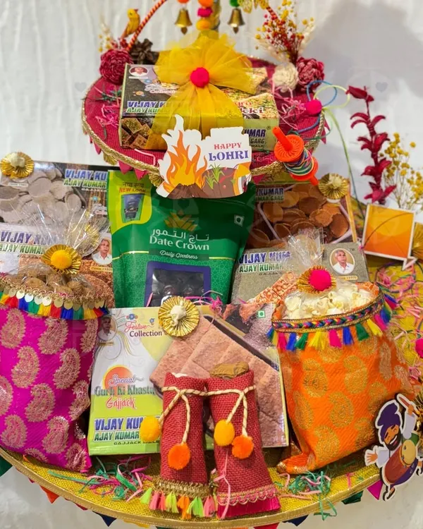 A grand Lohri hamper filled with all the essentials for the celebration. This platter includes packets of 'gajak', 'rewari', dates, and decorated 'potlis' of popcorn, all arranged beautifully.