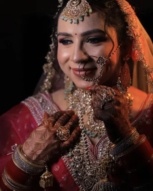 A close-up of a bride's stunning look, featuring a multi-layered kundan necklace, maang tikka, and nath. All this beautiful jewellery is available to rent along with the lehenga.