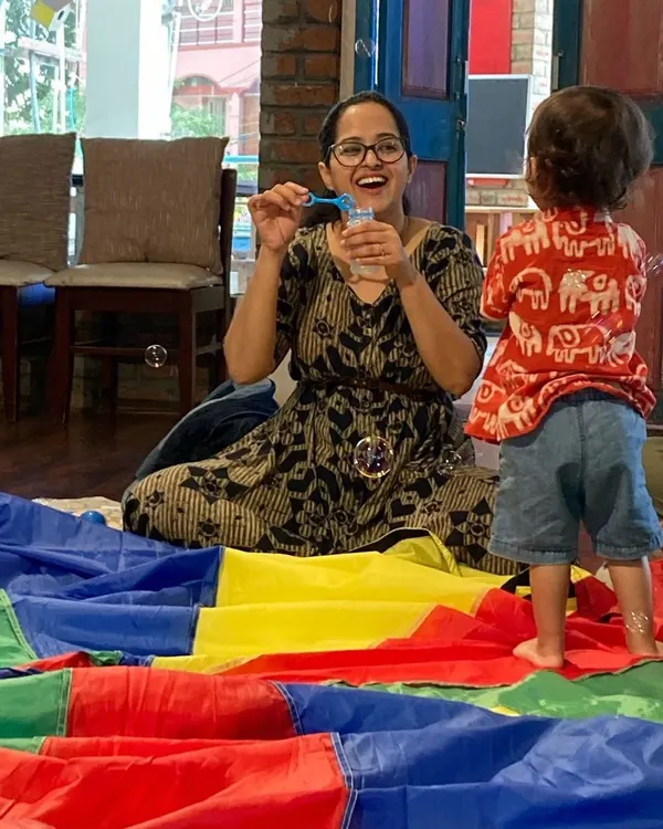 This is what pure joy looks like. In our sessions, it's not just about the babies having fun. It's about creating moments of connection and laughter for you, the parent, too. Here, a mother and child share a magical moment with bubbles and our colorful parachute.