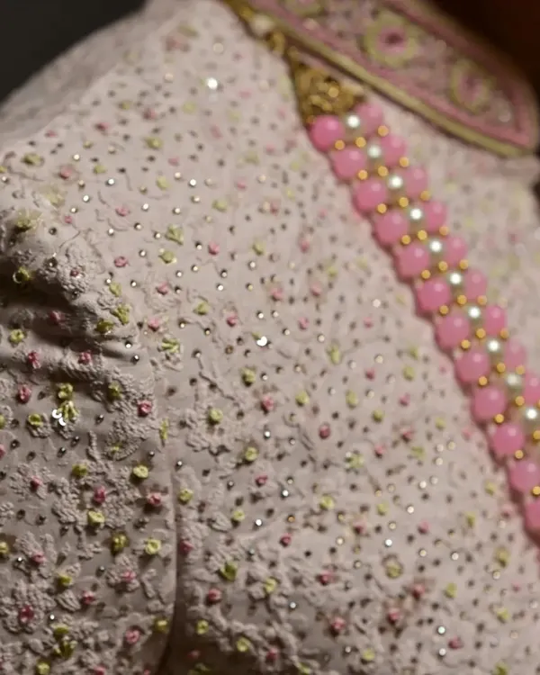 A close-up of the delicate embroidery and sequin work on this elegant pink sherwani.