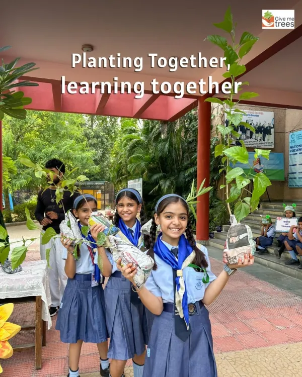 "Planting together, learning together." School students holding saplings they've prepared in newspaper pots. We teach them sustainable nursery techniques from a young age.