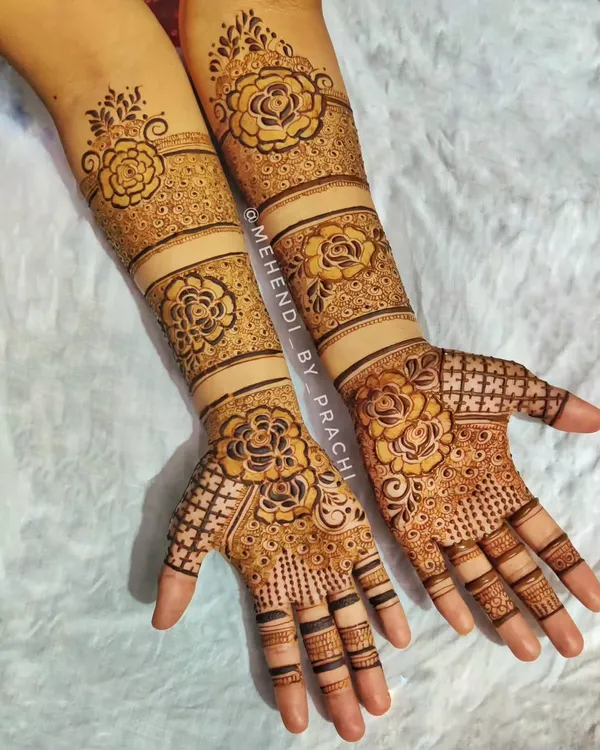 I love creating Indo-Western floral designs. This full-hand mehndi features bold rose patterns spaced out with clean bands and intricate net-like fillings, offering a modern yet traditional feel.