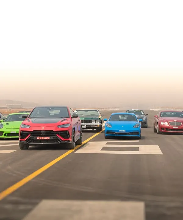A dynamic group shot from the Autocar India airport run, showing a collection of high-performance vehicles moving together on the tarmac.