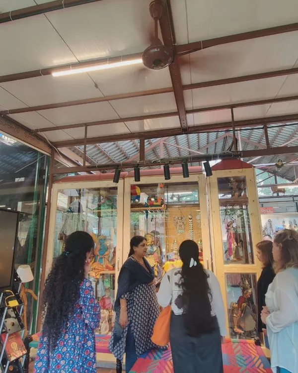 Guiding a group of students through the museum. Here, we are looking at our display cases, where I explain the different types of puppets and the stories they tell, making it an engaging educational experience.