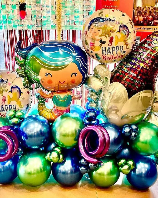 Dive into a magical underwater world with our mermaid-themed balloon bouquet. This arrangement features a beautiful mermaid foil balloon, a shimmering tail, and a sea of blue, green, and purple chrome balloons, perfect for any little ocean dreamer's birthday.