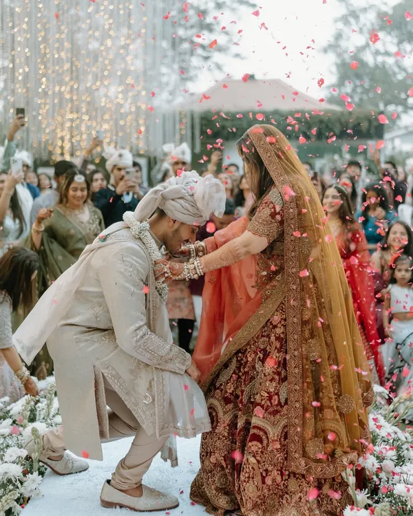A moment of playful surrender during the jaimala ceremony. The shower of petals and the joyous expressions capture the fun and excitement of this iconic wedding ritual.