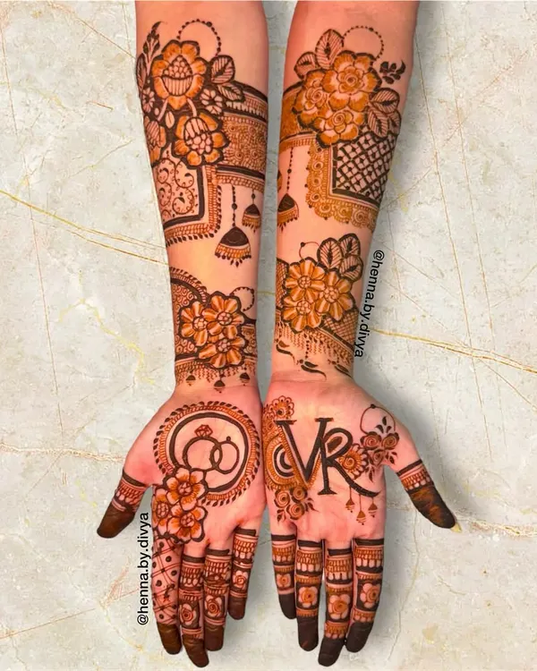 A perfect design for an engagement ceremony. This piece features the couple's initials 'VR', intertwined rings, and other celebratory motifs like jhumkas.