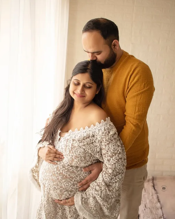 A cozy and intimate portrait of a couple. The soft lace robe and warm lighting create a feeling of comfort and love.