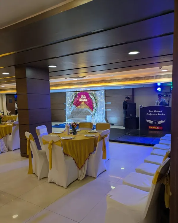 A view of the banquet hall during a Roka ceremony, showing the decorated stage in the background and the guest seating arrangement.