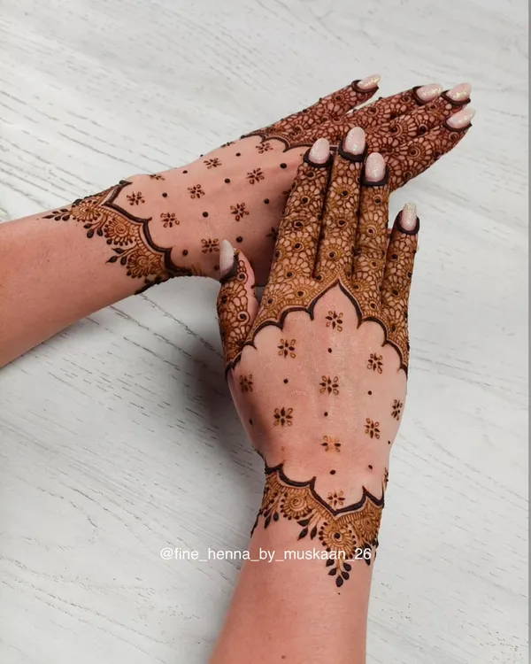 A beautiful example of a minimalist design. The scalloped border and scattered floral 'booti' create a chic and elegant look on the back of the hand.