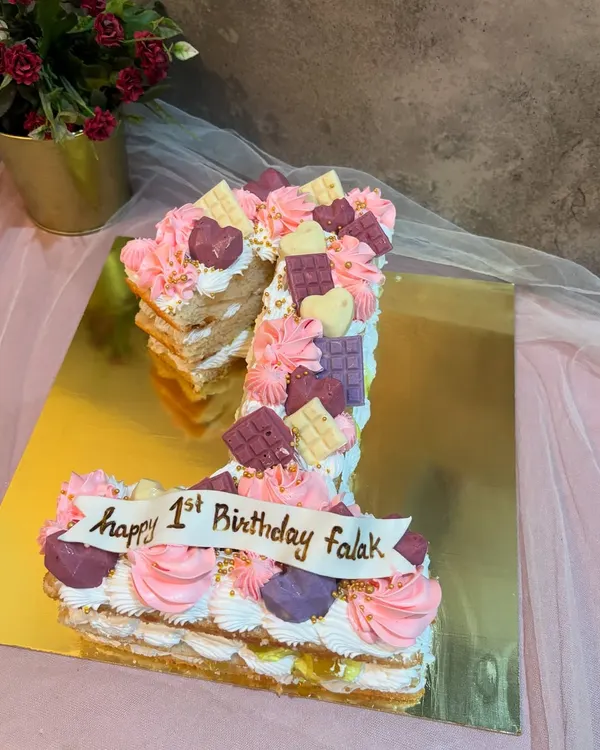 A number "1" monogram cake for a first birthday. This pull apart style cake is decorated with pink and purple frosting and little chocolate bars.