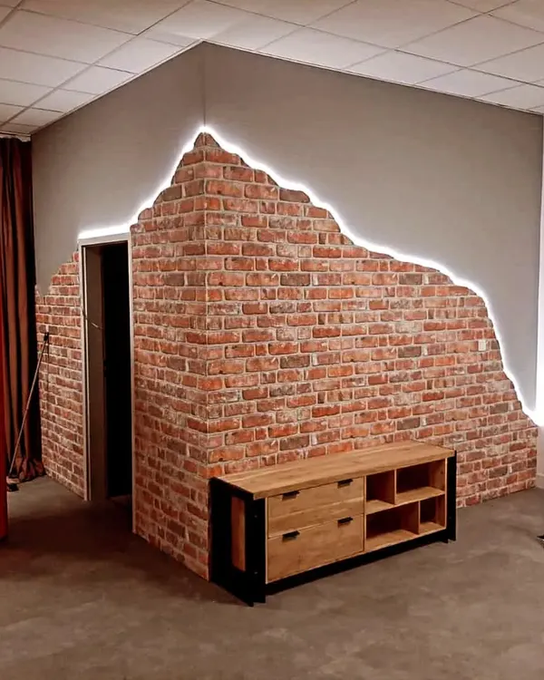 This unique accent wall combines a classic exposed brick texture with a modern "broken plaster" edge, highlighted by an LED strip for a dramatic effect.