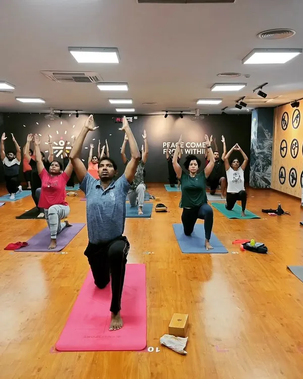 A room full of students lifting their hearts in Anjaneyasana (Low Lunge). This pose is fantastic for opening the hips and chest, and the collective energy makes it even more powerful.