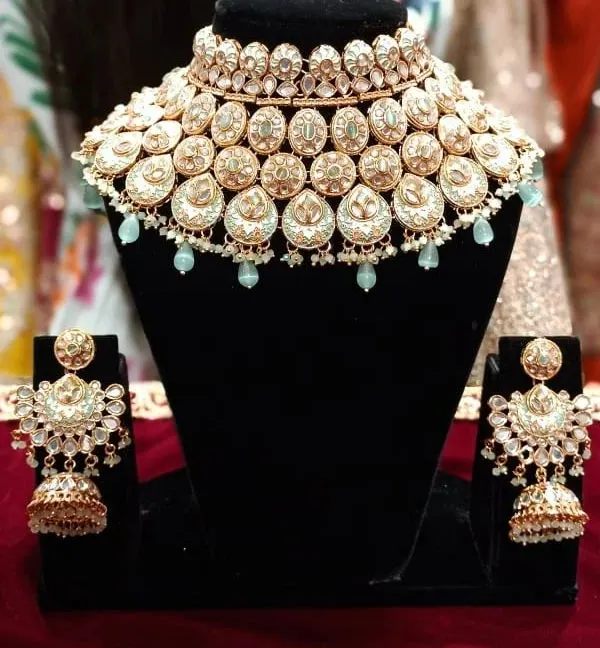 A beautiful Polki and Kundan choker set with matching jhumkas. The light mint green bead drops add a modern touch to this traditional design.