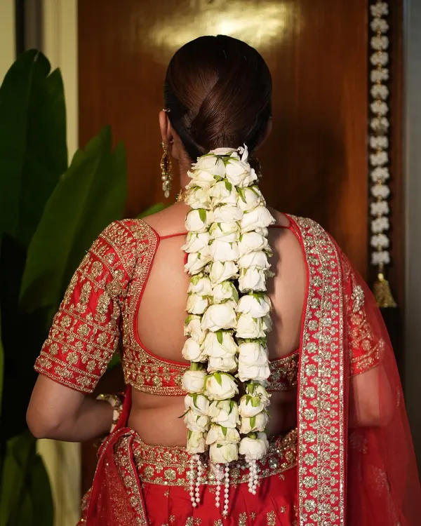 This is the hairstyle dreams are made of. A sleek, modern ponytail gets a traditional twist with a cascade of fresh white gajra and delicate pearl details, perfect for a main wedding ceremony.