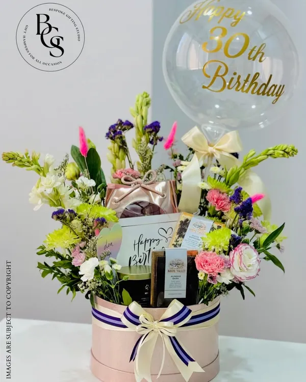 A spectacular 30th birthday hamper designed to wow. This large pink hatbox is overflowing with fresh flowers, curated gifts, and a personalized balloon, making it the ultimate celebratory statement piece.