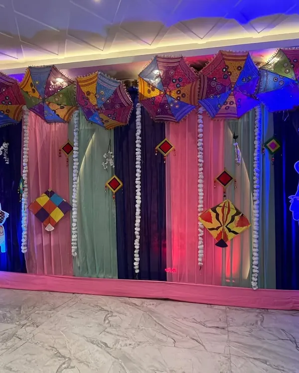 A vibrant stage setup for a Lohri celebration. We used colorful drapes, traditional Punjabi umbrellas (phulkari), kites, and character cutouts to create a festive atmosphere.