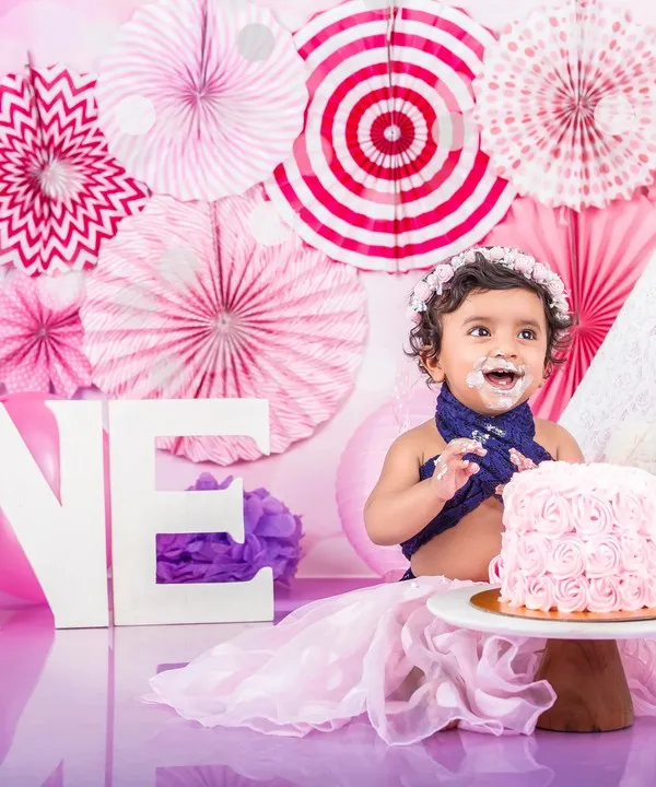 Her first taste of cake was a memorable one! This little girl is having a blast at her pink-themed cake smash, complete with a teepee and a 'ONE' sign.