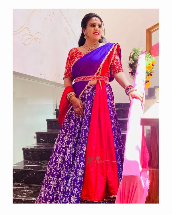 Our client looks absolutely stunning in this custom red and purple half-saree. The outfit features a heavily embroidered red blouse and a rich purple brocade skirt.
