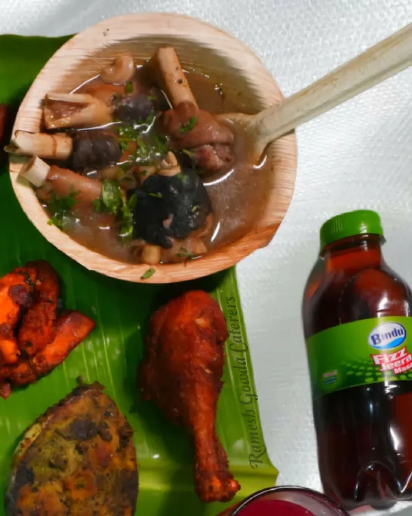 A close-up of our non-veg meal, featuring Mutton Bone Soup, Chicken Kebab, and a fried chicken leg piece, all served on a fresh banana leaf.