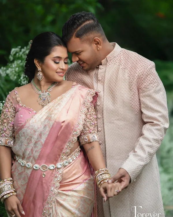 A beautiful moment between this engaged couple. Her pastel pink saree with a 3D floral blouse is perfectly complemented by his elegant pink sherwani.