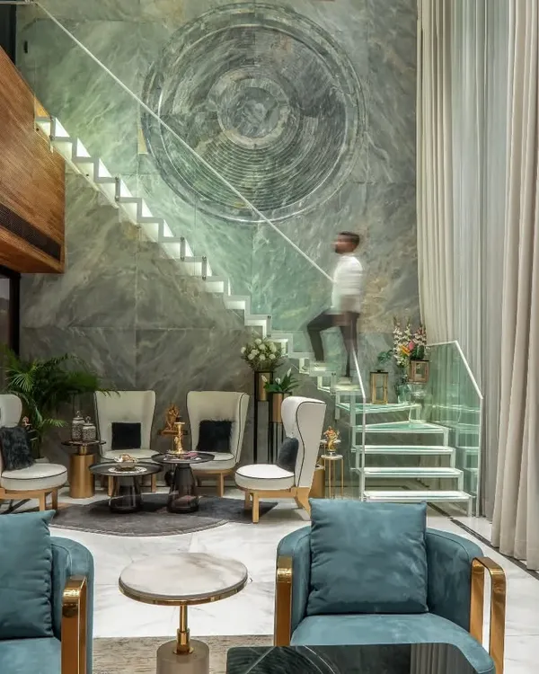 We designed this double-height living area to be a statement of modern opulence. The floor-to-ceiling marble wall features a custom art relief, serving as a dramatic backdrop to a floating staircase, creating a space that is both grand and inviting.