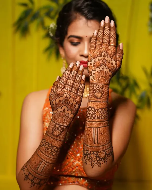 A beautiful bride posing with her mehndi. The design features traditional Indian motifs with delicate floral work, and the rich orange stain shows the quality of my henna.