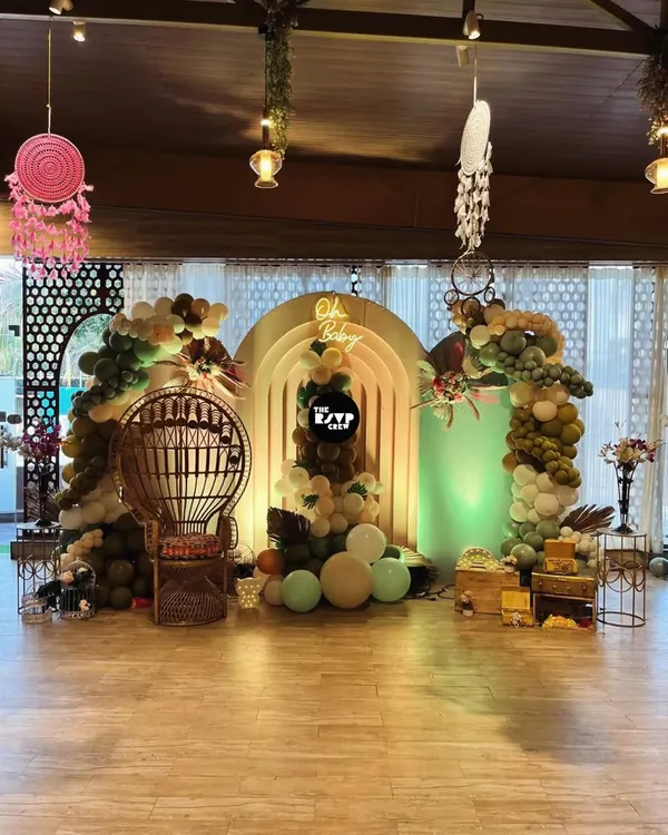 Our signature boho baby shower setup. We combined earthy-toned organic balloon arches with pampas grass and a custom "Oh Baby" neon sign to create a warm, inviting photo zone. The wicker peacock throne makes the mom-to-be the true center of attention.