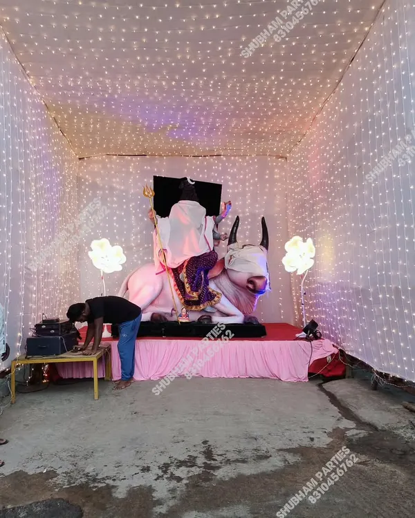 A beautiful pandal setup for the Ganapati festival, featuring a large idol and a backdrop illuminated with strings of fairy lights.