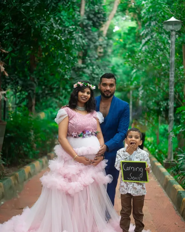 A complete family portrait for a maternity announcement. We provided the pink ruffle gown for mom, a stylish blue suit for dad, and a cute outfit for the big brother-to-be.