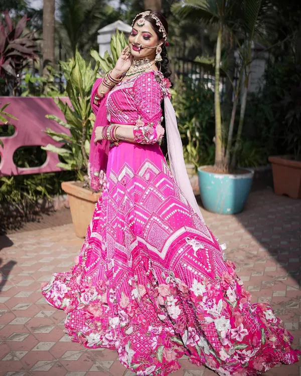 A stunning bride in a vibrant pink lehenga, perfect for a grand wedding. The makeup is glamorous yet fresh, with a focus on radiant skin and beautifully defined eyes.