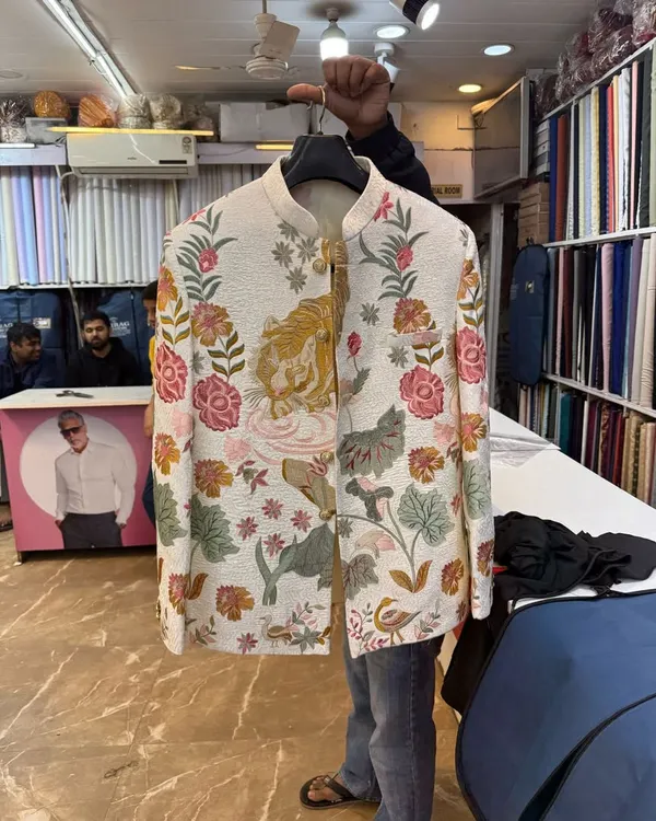 This is a special custom piece we created based on a client's unique design. The off-white Jodhpuri jacket features detailed, multi-colored floral and tiger embroidery, showing how we can bring any design idea to life.