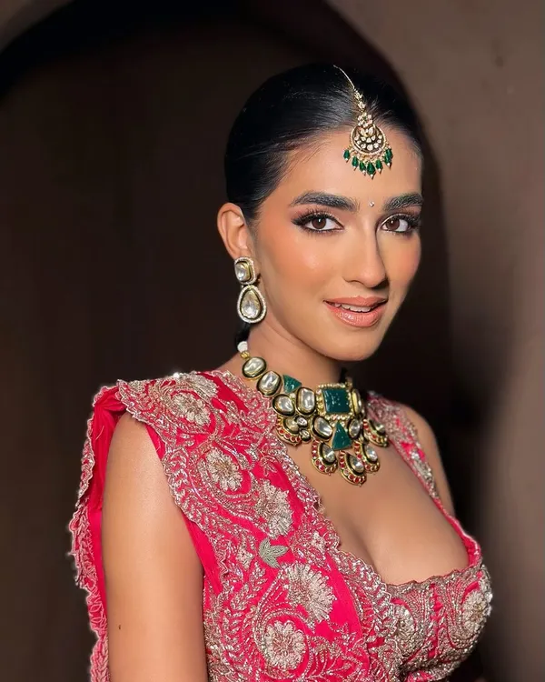 A close-up of a modern bride in a bold red lehenga. The makeup features softly sculpted eyes and glowing skin, creating a look that is both elegant and striking, perfect for a royal-inspired wedding.