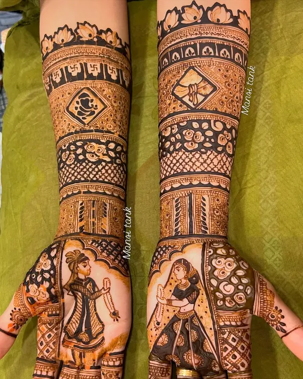 A complete view of a personalized bridal mehendi. One hand features a portrait of the groom, while the other has the bride, along with auspicious symbols like a Ganesha and swastika on the arms.