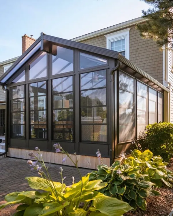 A beautiful example of a gable-roof sunroom addition that complements the existing home's architecture. The floor-to-ceiling glass panels and durable frame create a spacious, all-season room for family enjoyment.